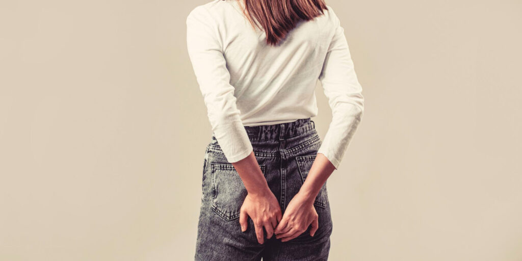 Kobieta trzymająca ręce na bolącej i piekącej pupie