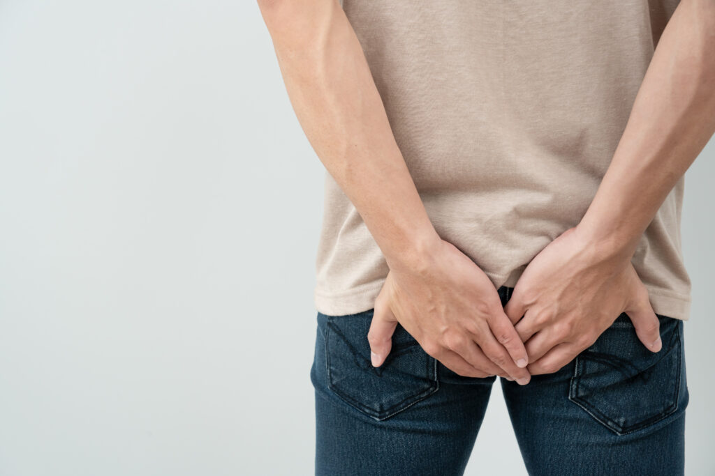 Mężczyzna trzymający swoje ręce na bolącej pupie