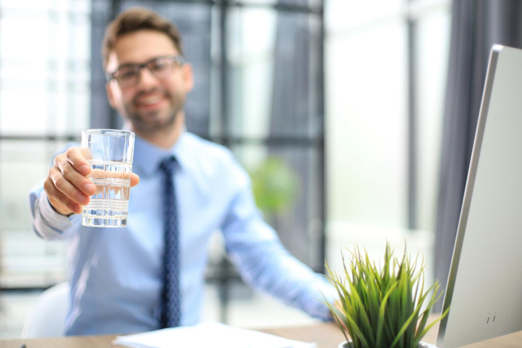 Mężczyzna pijący wodę ze szklanki w trakcie pracy w biurze